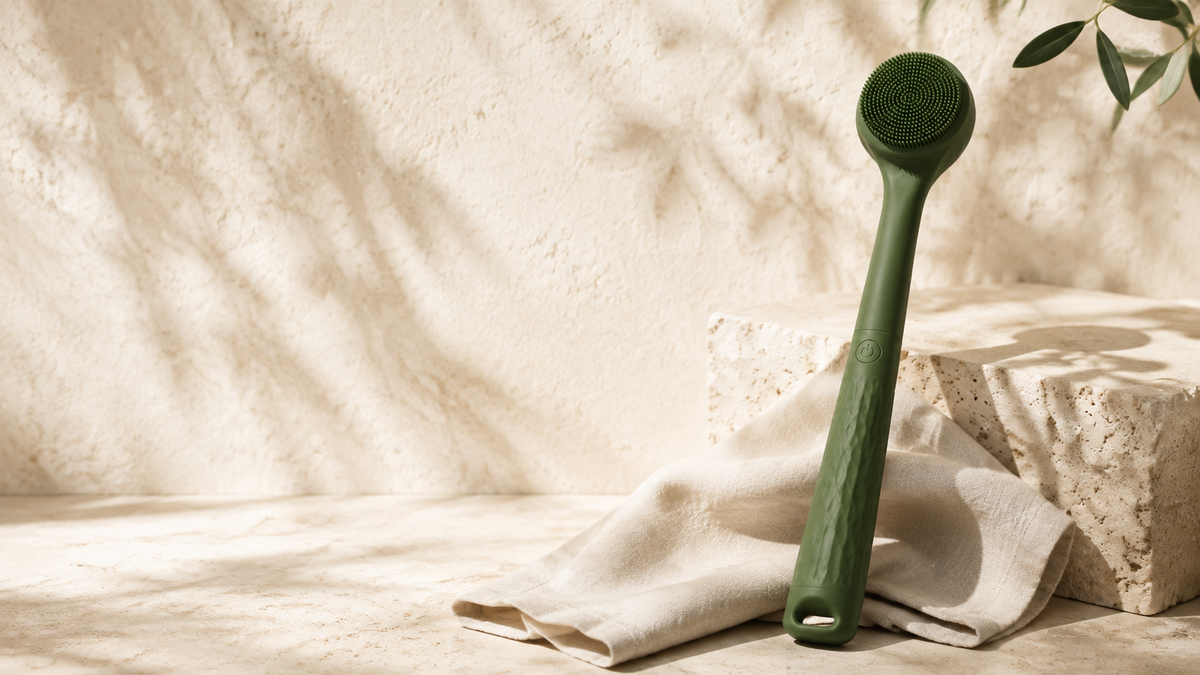 Green Bristlewell electric body brush in a warm stone bathroom setting